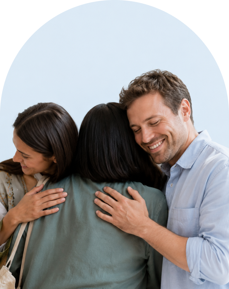 hugging Three friends sharing a warm group hug, with smiles and light blue background, facing outward from the center person’s back
